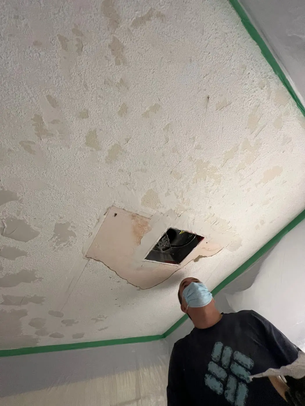 Stipple letting go across the whole ceiling, plus a torn-open fan opening. Note the plastic and tape — that goes up first.